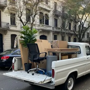 Camioneta de flete cargada con sillas, plantas y cajas de oficina