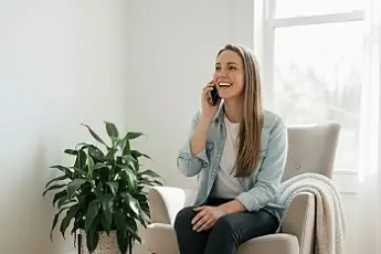 Mujer llamando por teléfono sentada en un sillón